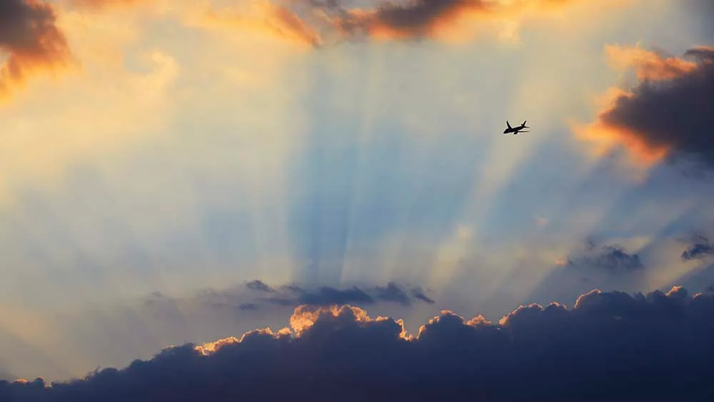 Plane flying towards sunset and crepuscular rays, London, England, UK Sunbeams, or crepuscular rays, over London © Getty Images