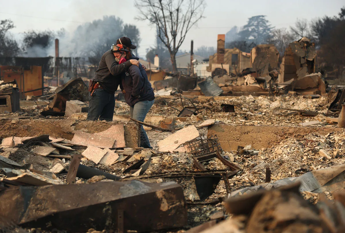 Khaled Fouad (L) and Mimi Laine (R) embrace as they inspect a family member's property that was destroyed by Eaton Fire on January 09, 2025 in Altadena, California.