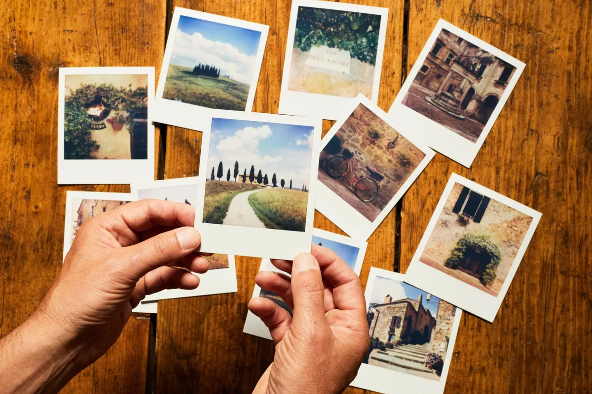 A man arranging a selection of photos of Tuscany on a table.