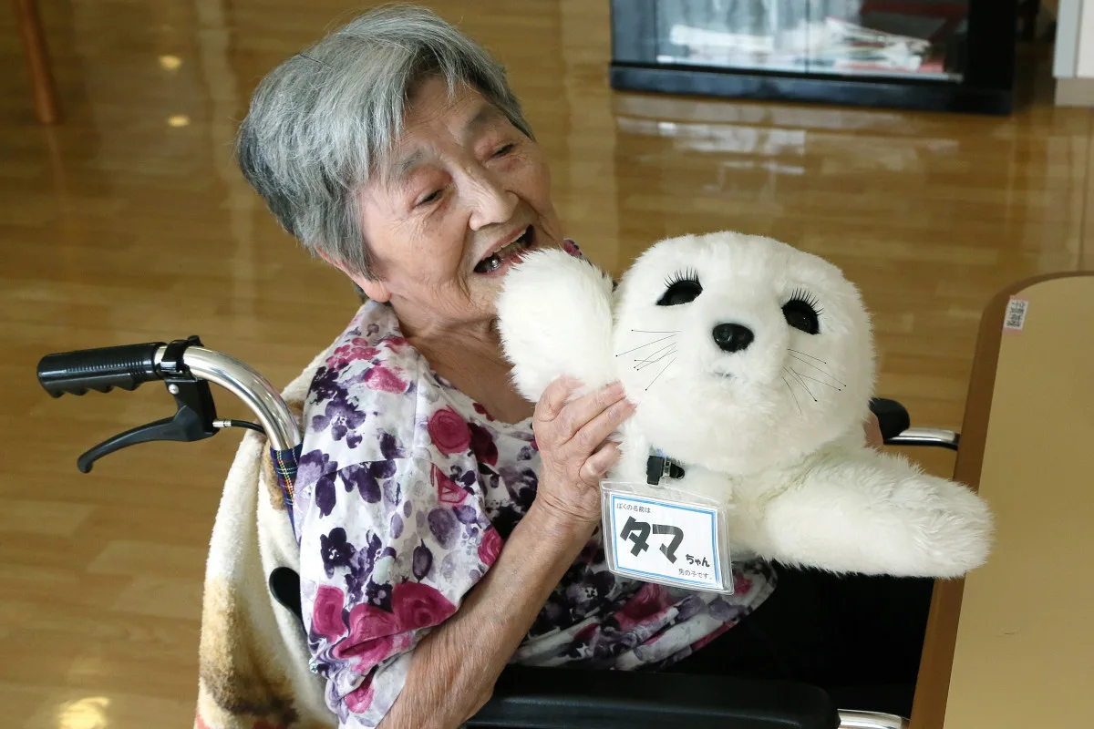 A resident of a nursing home plays with nursing-care robot 'Paro' at the nursing home in Yokohama city, Kanagawa prefecture, Japan